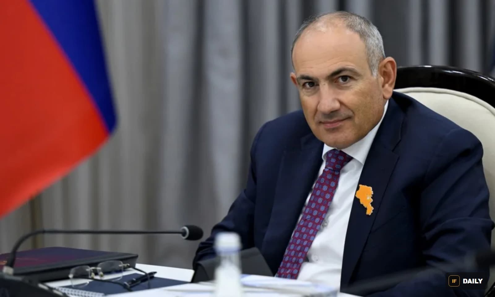 Armenian Prime Minister Nikol Pashinyan seated at a table with an Armenia flag pin on his jacket
