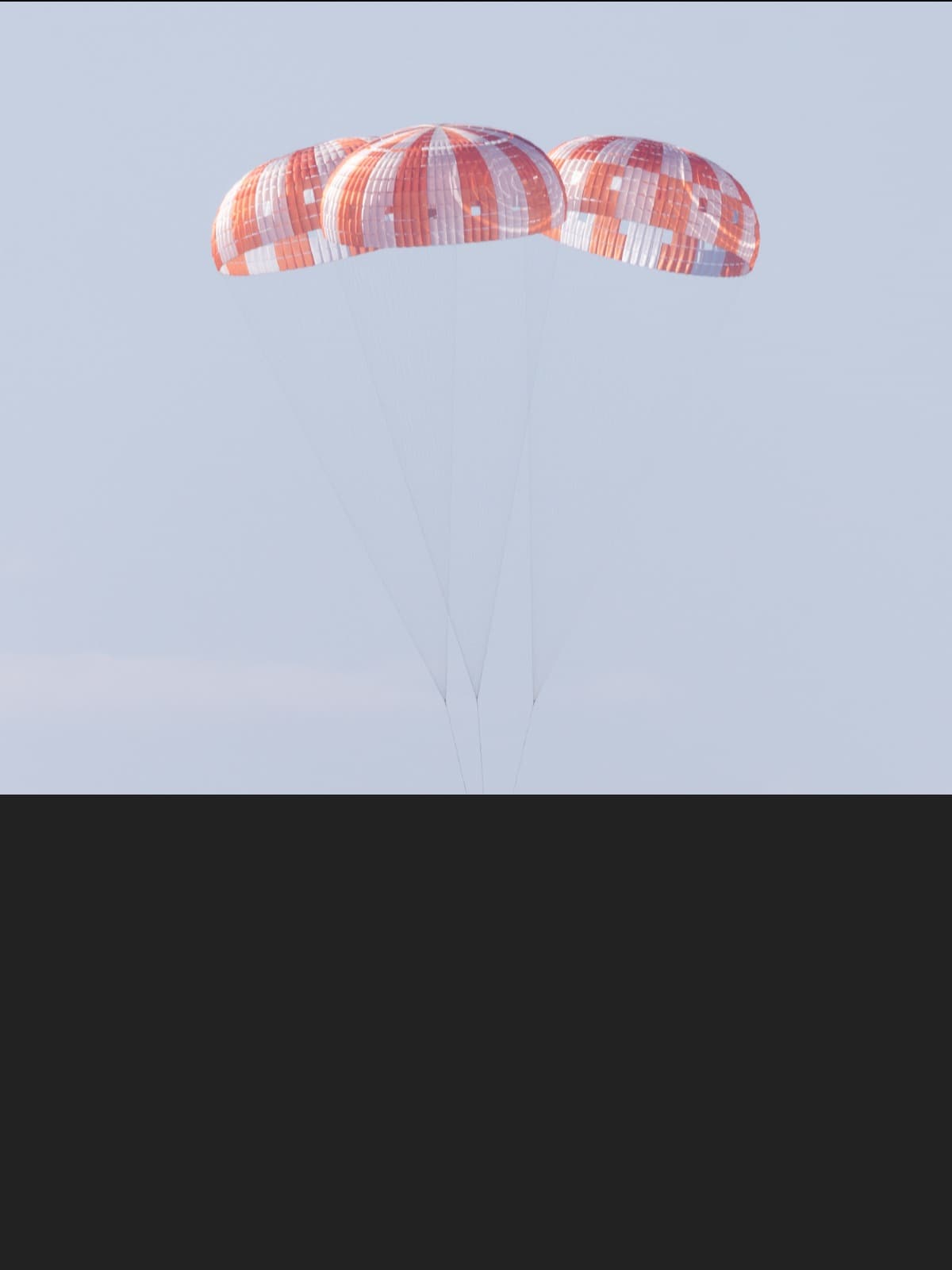 The Orion spacecraft descending under three orange-and-white parachutes toward the ocean