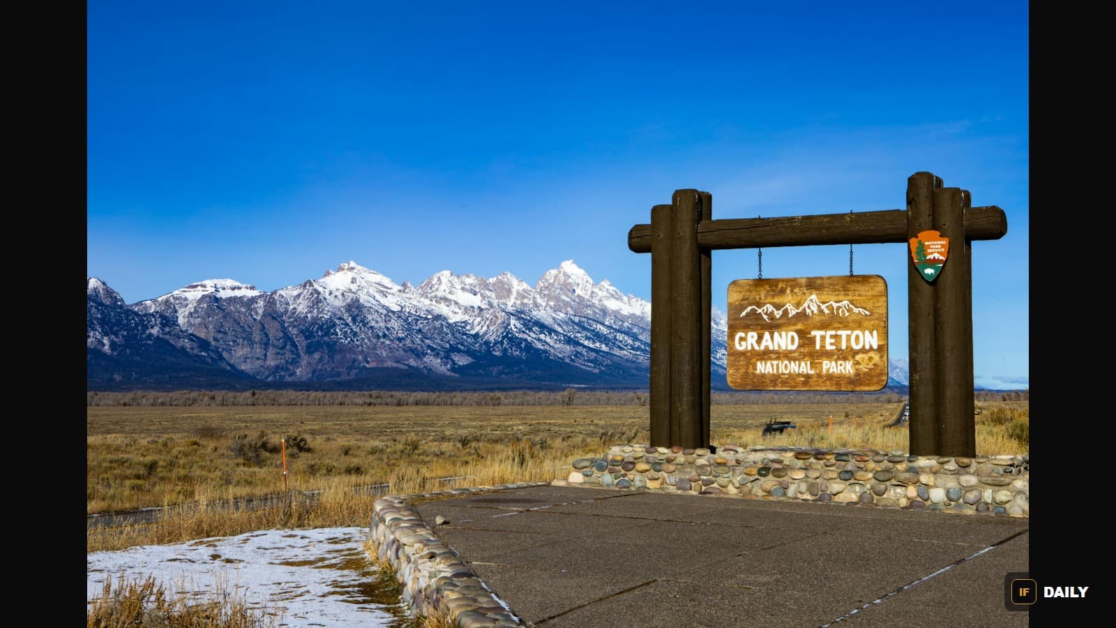 The wooden Grand Teton National Park entrance sign with snow-capped mountains in the background