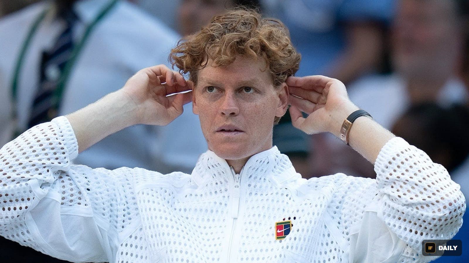Jannik Sinner adjusting his cap while wearing a white Wimbledon outfit on court