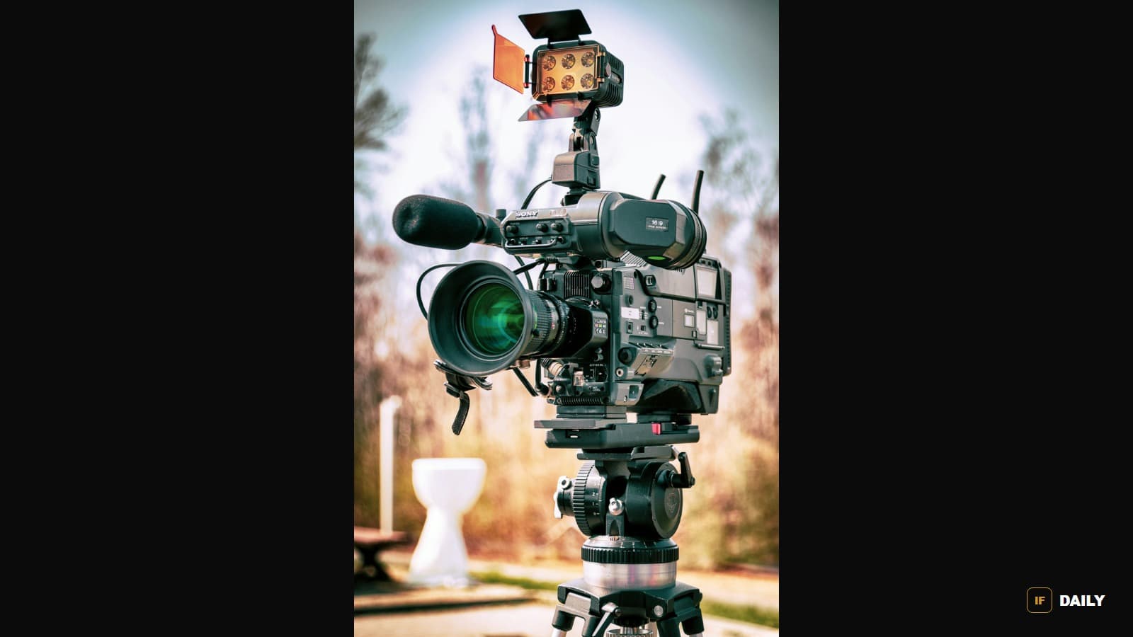 A professional broadcast video camera with a boom microphone and light rig mounted on a tripod